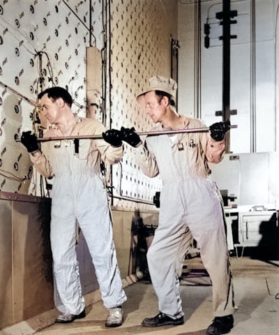 Workers using a rod to push uranium slugs into the loading face of the X-10 graphite reactor, Oak Ridge, Tennessee, United States, date unknown [Colorized by WW2DB]