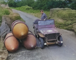 A member of the 2107th Ordinance-Ammo Battalion inspecting a store of 4000-pound bombs, some under camouflage netting, along the roadside at the Sharnbrook Ordinance  Depot, Bedfordshire, England, UK.  July 1943