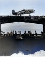 Starboard side view of the carrier Yorktown (Essex-class) with an F6F-3 Hellcat fighter of VF-1 on the fight deck above the athwartship hangar deck catapult, June 1943.