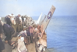 Crews attach lines to an F6F Hellcat hanging over the edge of the training aircraft carrier USS Sable on Lake Michigan, United States, 1945.