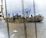 Liberty ship unloading two CCKW trucks and other supplies onto a Rhino cargo barge off the Normandy beaches, Jun 1944.