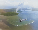 Smoke rising from Colonia Harbor on Yap, Caroline Islands as a TBM Avenger from the carrier Yorktown (Essex-class) flies overhead, 25-28 July 1944