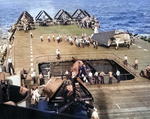 F6F Hellcat fighter coming up on the Number 3 flight deck elevator on USS Yorktown (Essex-class), early 1945. Note TBM-3 Avengers and SB2C Helldivers also on deck.