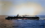 An F6F Hellcat landing aboard Independence-class carrier USS Cabot in the Pacific while a cruiser steams off the beam, 1945.