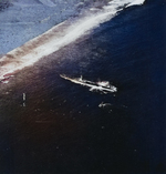 Submarine USS Harder with her bow against the reef off Woleai, Caroline Islands, 1 Apr 1944 as a rescue party went ashore to rescue aviator Ensign John Galvin on the beach. Note SOC Seagull seaplane.