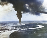 Strike photo from USS Ticonderoga aircraft showing burning oil storage tanks on the banks of the Mekong River in Saigon, French Indochina (Ho Chi Minh City, Vietnam), 12 Jan 1945.