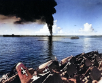 Smoke rising from the overturned and burning fleet oiler USS Mississinewa in Ulithi Lagoon, 20 Nov 1944 as seen from the carrier Lexington (Essex-class). Ticonderoga is at left and hospital ship Solace is at right.