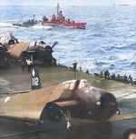 Fletcher-class destroyer USS Harrison steaming alongside carrier USS Bennington as Bennington’s TBM Avengers run up their engines, early 1945 in the Western Pacific.