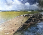 The capsized minelayer USS Oglala still tied to the dock after being sunk in the Japanese air attack on Pearl Harbor, Hawaii, mid-Dec 1941 photo. Note the checkerboard paint scheme of the harbor ferry Nihoa.