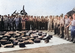 Crew and aviators of USS Bogue looking at bales of raw rubber recovered from the debris field after sinking Japanese submarine I-52 in the mid-Atlantic, 24 Jun 1944. Note the FM-2 Wildcat.