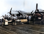 Flight deck crews of USS Wasp preparing a plywood-shrouded Mark XIII torpedo for a TBM Avenger aircraft for strikes in Taiwan-Philippine area, 13 Oct 1944; note TBM-1C Avenger and F6F-5 Hellcat