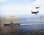 SB2C Helldivers flying over USS Essex during the Okinawa campaign, May 1945; USS Bunker Hill, USS Langley, and other vessels in background