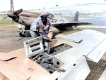 An African-American US Army personnel loading ammunition for a .50 caliber machine gun in the wing of a P-51 Mustang fighter, Italy, Sep 1944