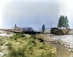 US Army soldier standing next to a C-47 Skytrain wreck, near Bastogne, Belgium, circa early 1945