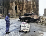 Corporal Luther E. Boger of US 82nd Airborne Division reading a warning sign in front of Cologne Cathedral, Köln (Cologne), Germany, 4 Apr 1945; note Thompson submachine gun and Panther tank wreck