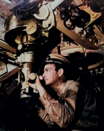 A US Navy officer at periscope in control room of submarine, circa 1942