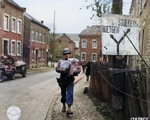 US Army Sergeant Joseph H. Kadlec with Christmas holiday packages, Zweifall, Germany, 14 Nov 1944; note street sign for Roetgen (to the southwest) and Stolberg (to the north-northwest)