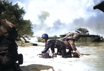 Two US Marines crawling into position on a Saipan, Mariana Islands beach after their landing craft was hit by Japanese mortar, 15 Jun 1944; note LVT(A)-4 Water Buffalo in background