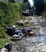 Three dead German soldiers laying on a road near Sainteny, Normandy, France, 16 Jul 1944; note Volkswagen-made Schwimmwagen vehicle and two American soldiers in background