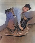 Aviation Ordnanceman 1st Class Billy Simms inspecting the wing guns of a fighter aircraft aboard USS Anzio, 18 Apr 1945