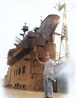 Japanese sailor aboard carrier Junyo signaling an approaching tug, Sasebo, Japan, 19 Oct 1945