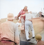 SBD Dauntless crewman Alva Parker, having suffered neck and shoulder shrapnel wounds over Rabaul, New Britain, being helped from the aircraft after landing on USS Saratoga, 5 Nov 1943