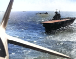 USS Yorktown seen from a TBD-1 aircraft, Pacific Ocean, Apr 1942; note F4F-3 Wildcat fighter preparing for takeoff, and fleet oiler USS Guadaloupe, a destroyer, and a cruiser just beyond