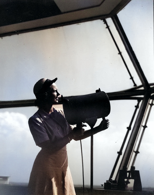 WAVES Specialist 2nd Class Jane Rockman using a control tower signal lamp to flash landing instructions to an incoming plane, Naval Air Station, Norfolk, Virginia, United States, circa 1943-1945 [Colorized by WW2DB]