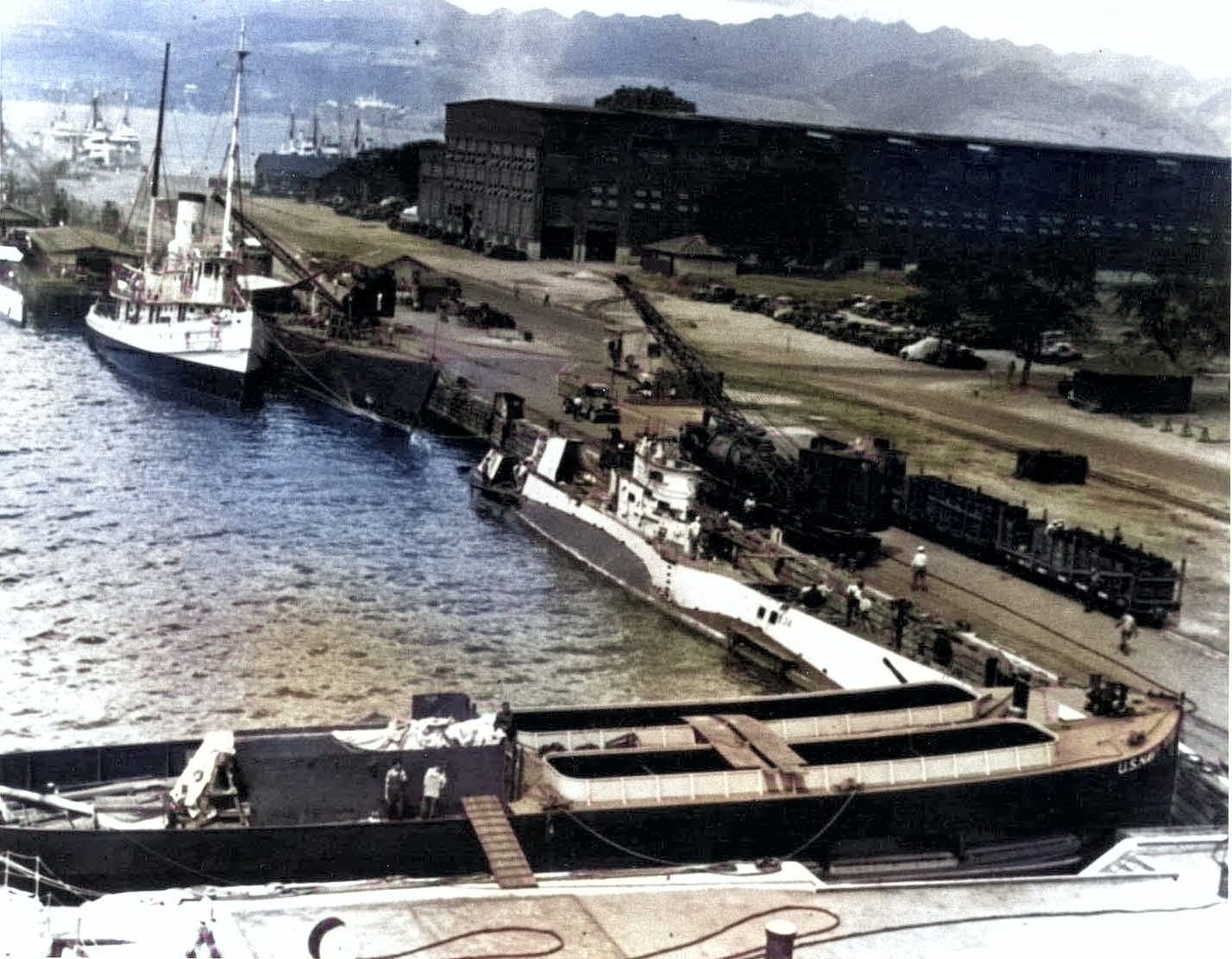 USS S-34 tied up to wharf in Pearl Harbor, US Territory of Hawaii, late 1930s; note railcar carrying new batteries for S-34, and a Balao-class submarine moored nearby [Colorized by WW2DB]
