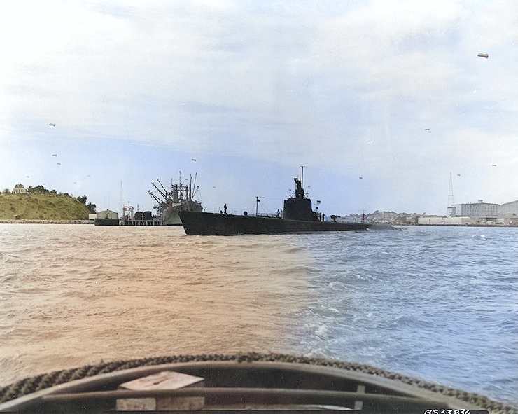 USS Wahoo departing Mare Island Naval Shipyard, Vallejo, California, United States, 10 Aug 1942; note munitions ship USS Shasta at the pier and barrage balloons overhead. [Colorized by WW2DB]