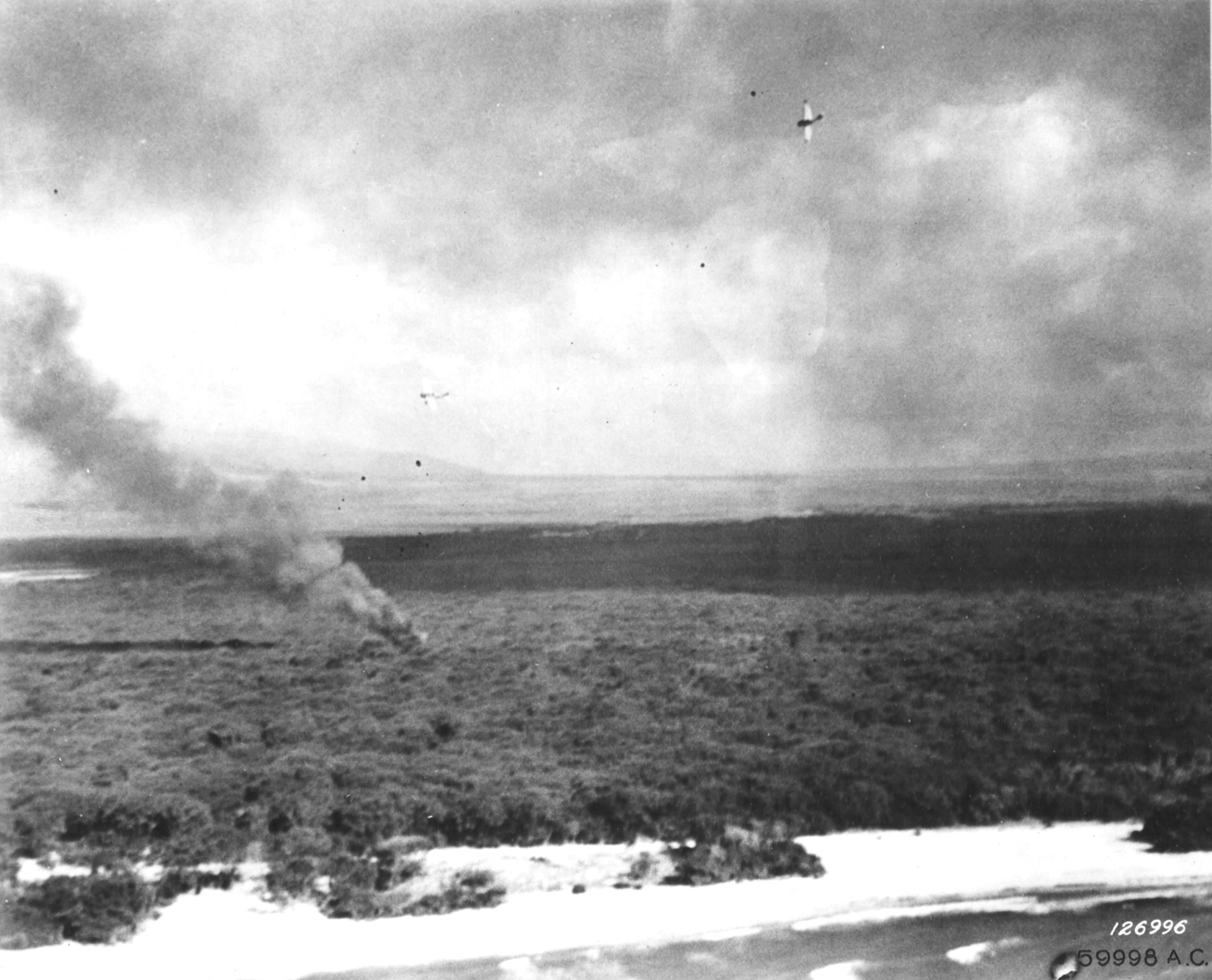 Japanese A6M2 Zero fighter flying above a shot-down US fighter, near Ewa Marine Corps Air Station, Oahu, US Territory of Hawaii, 7 Dec 1941; photo taken by a B-17 bomber crew