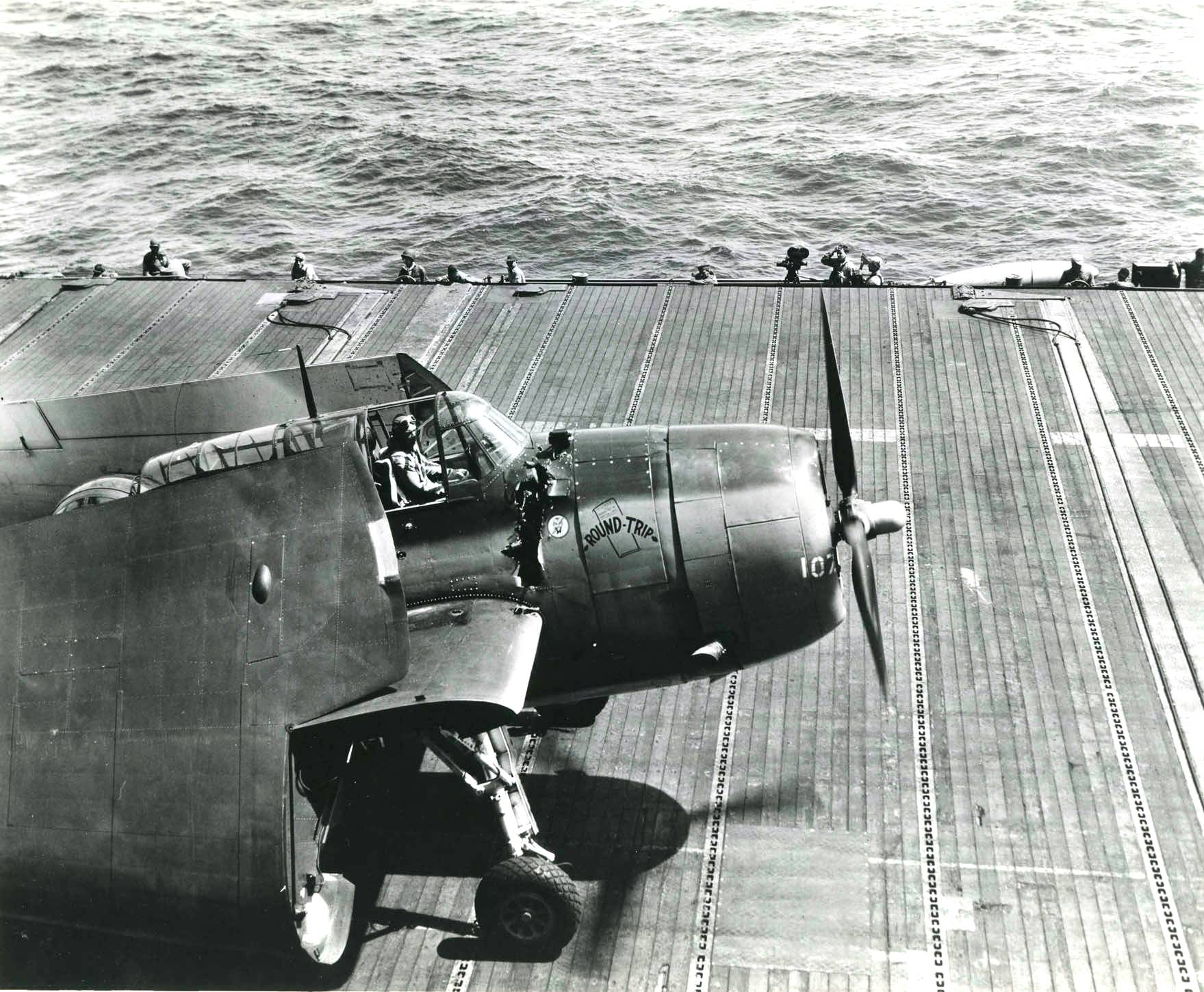 US Navy pilot Ensign C. V. 'Vern' Higman landing on Ticonderoga after a raid on Ormoc Bay, Philippine Islands, 11 Nov 1944; note AA damage on TBM-3 Avenger aircraft 'Round Trip Ticket'