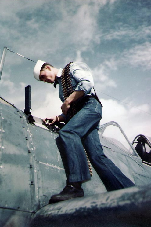 US Navy ordnanceman loading .50 caliber ammunition for a F2A Buffalo fighter, Naval Air Station Miami, Florida, United States, 9 Apr 1943