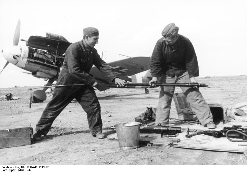German crewmen Hoffmann and Berger cleaning the machine gun barrel of Bf 109 fighter W. Nr. 8673, which belonged to Hans-Joachim Marseille, Martuba, Libya, Mar 1942