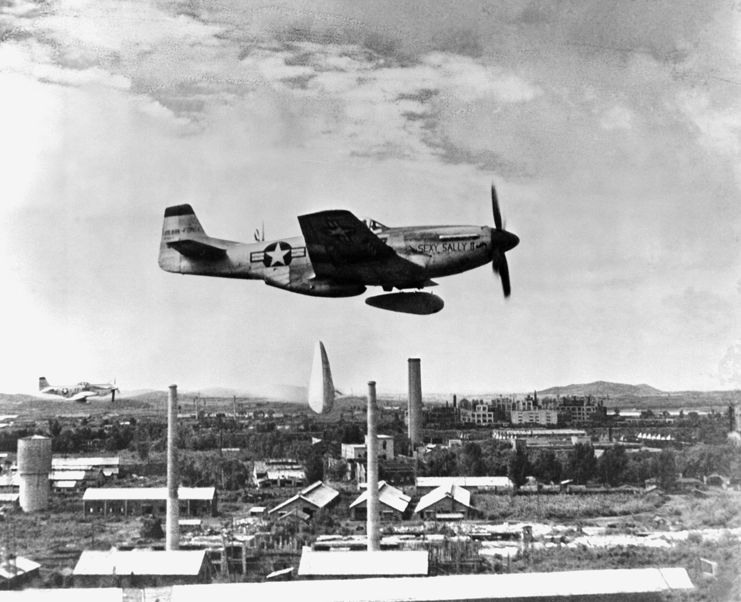 P-51 Mustang fighter of the US 5th Air Force dropping two napalm bombs in North Korea, 1 Jan 1951