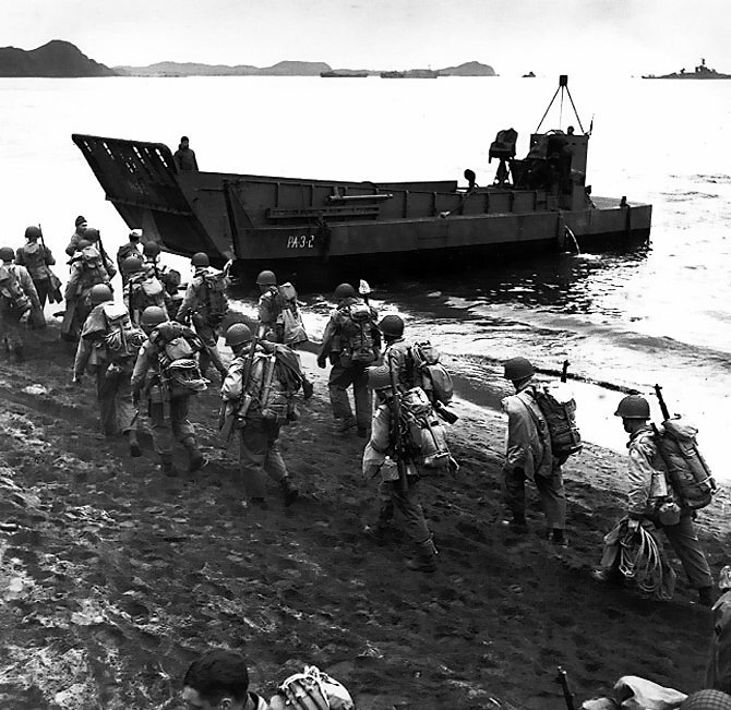 American troops marching up the beach at Adak, Aleutian Islands during pre-invasion loading for the Kiska invasion, 13 Aug 1943; note LCM landing craft, USS Pennsylvania, and M1 Garand rifles