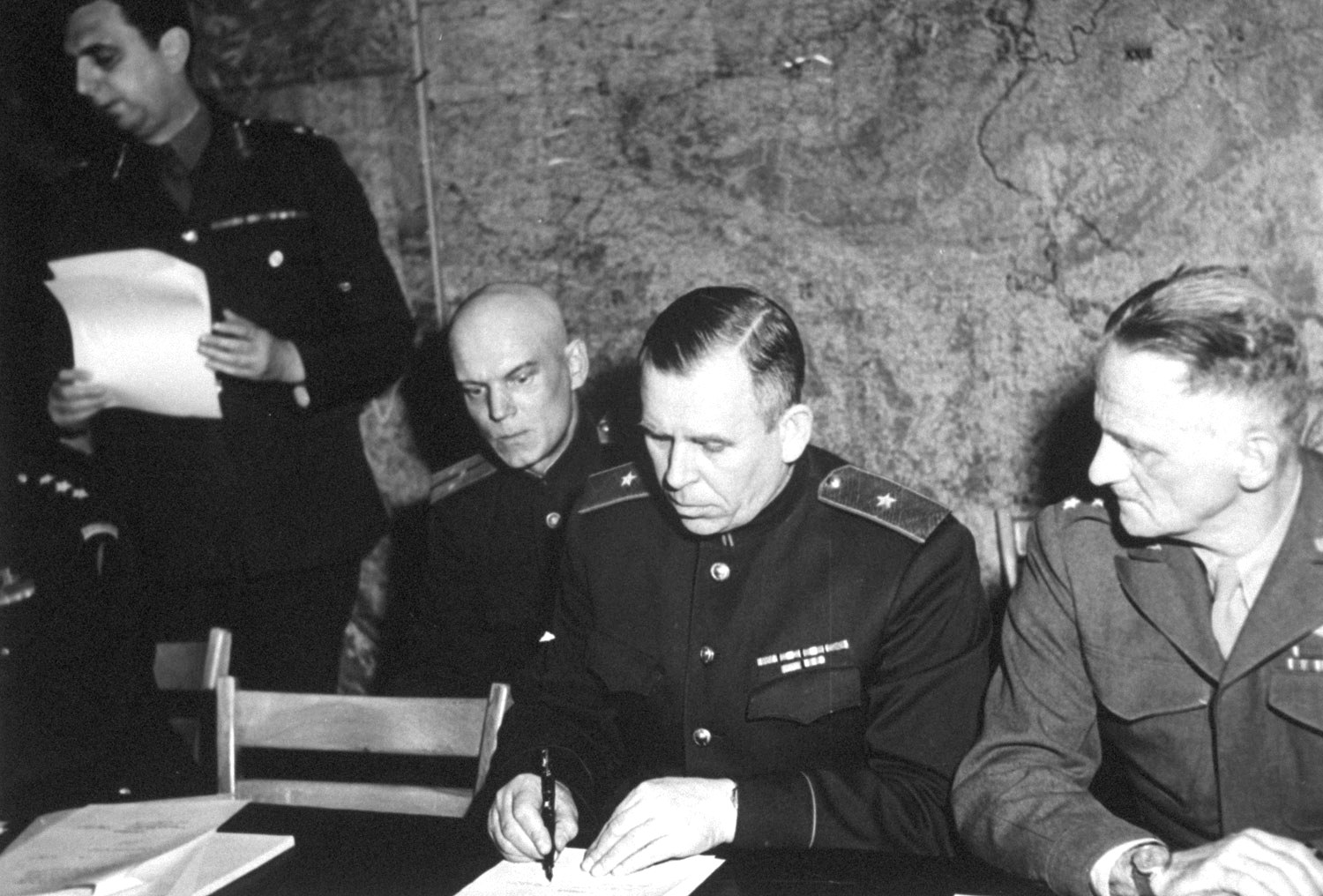 Soviet General Ivan Susloparov signing the documents of Germany's surrender, Reims, France, 7 May 1945. His aide is on the left and USAAF LtGen Carl Spaatz on the right.