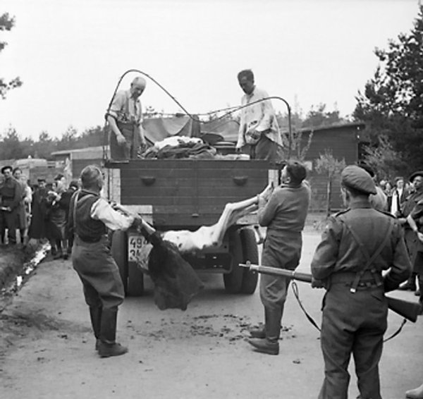 A British soldier looked on while SS Guards were forced to load bodies of Bergen-Belsen Concentration Camp victims onto a truck, Germany, 17-18 Apr 1945