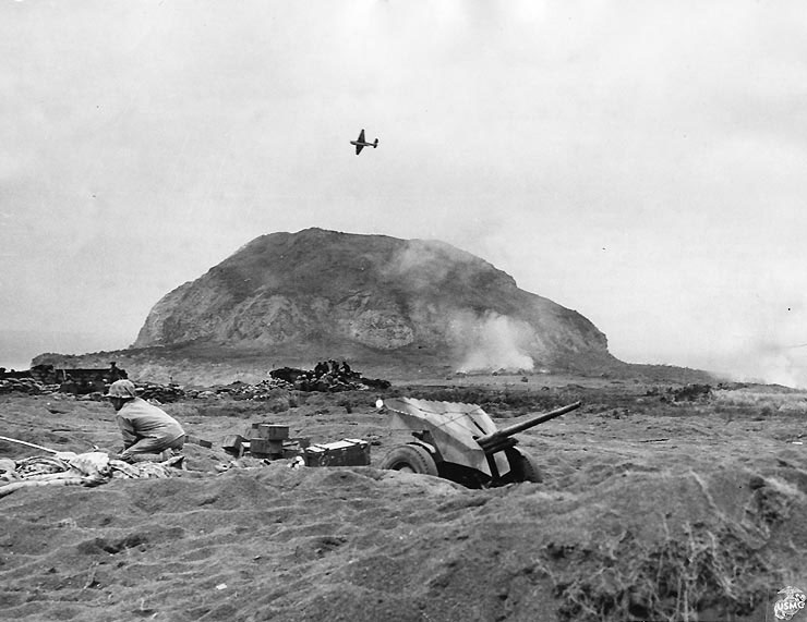 A 37mm gun on Iwo Jima beach with Mount Suribachi in background, 20 Feb 1945; note the TBM Avenger flying overhead
