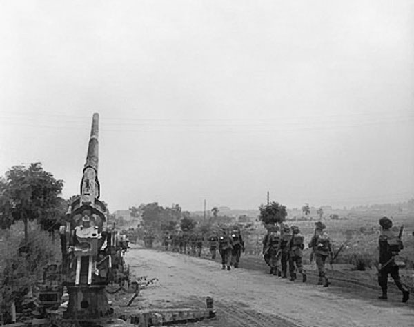 Infantry of British 50th (Northumbrian) Division moving up past a knocked-out German 88mm gun near 'Joe's Bridge' over the Meuse-Escaut Canal, Belgium, 16 Sep 1944