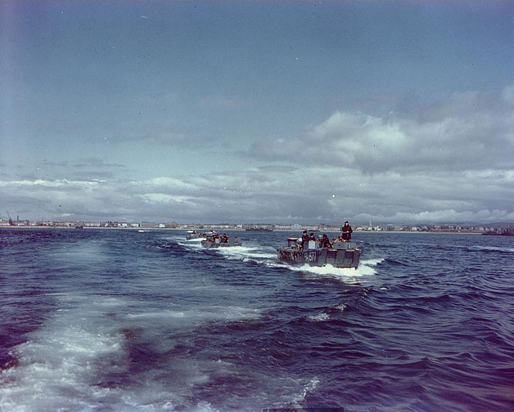 Royal Navy LCA landing craft churn through the waters of a British port, taking American troops to a waiting ship during preparations for the Normandy invasion, circa May-Jun 1944