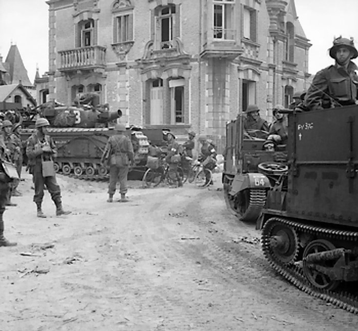 British Universal Carriers with deep wading screens and a Churchill AVRE tank passing through La Breche, France, 6 Jun 1944