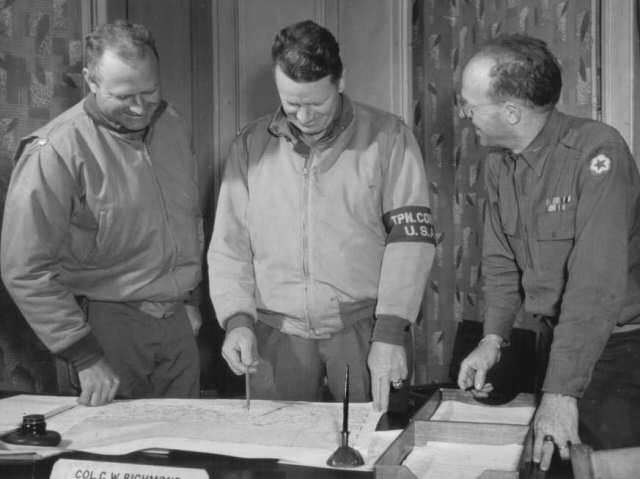 Commander of the US Army Transportation Corps Colonel C. W. Richmond (center) examining a road map at the 'Red ball' headquarters, Alençon, France, Aug-Nov 1944