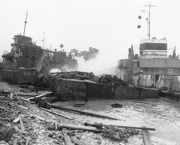 Broached landing craft during the Normandy storm, probably at Omaha Beach, 21 Jun 1944; note LST-543 in background