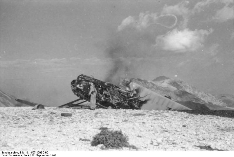 German airborne trooper destroying a crash-landed glider, Gran Sasso, Italy, 12 Sep 1943
