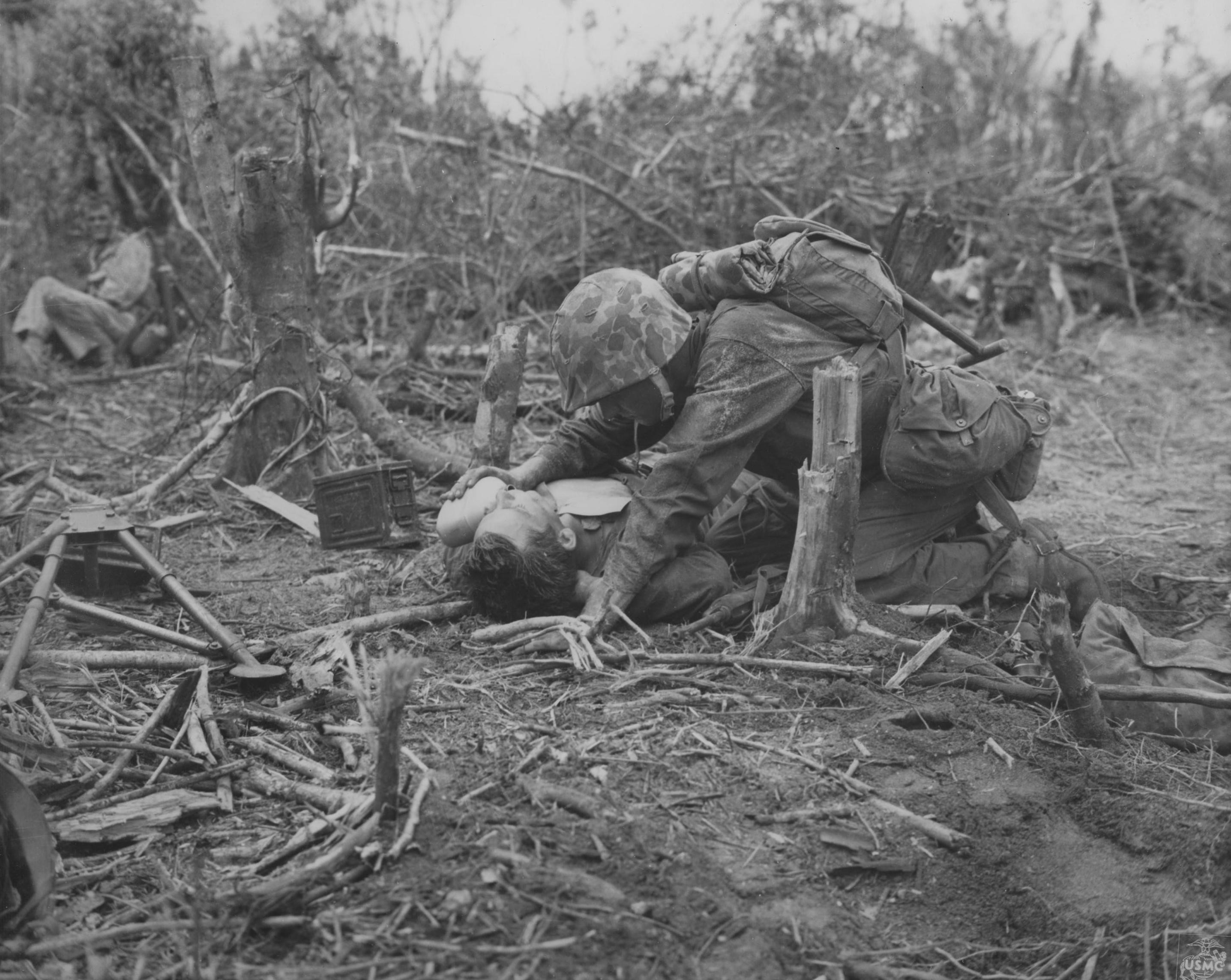 An US Marine giving his wounded comrade a drink of water from a canteen, Peleliu, Palau Islands, Sep 1944