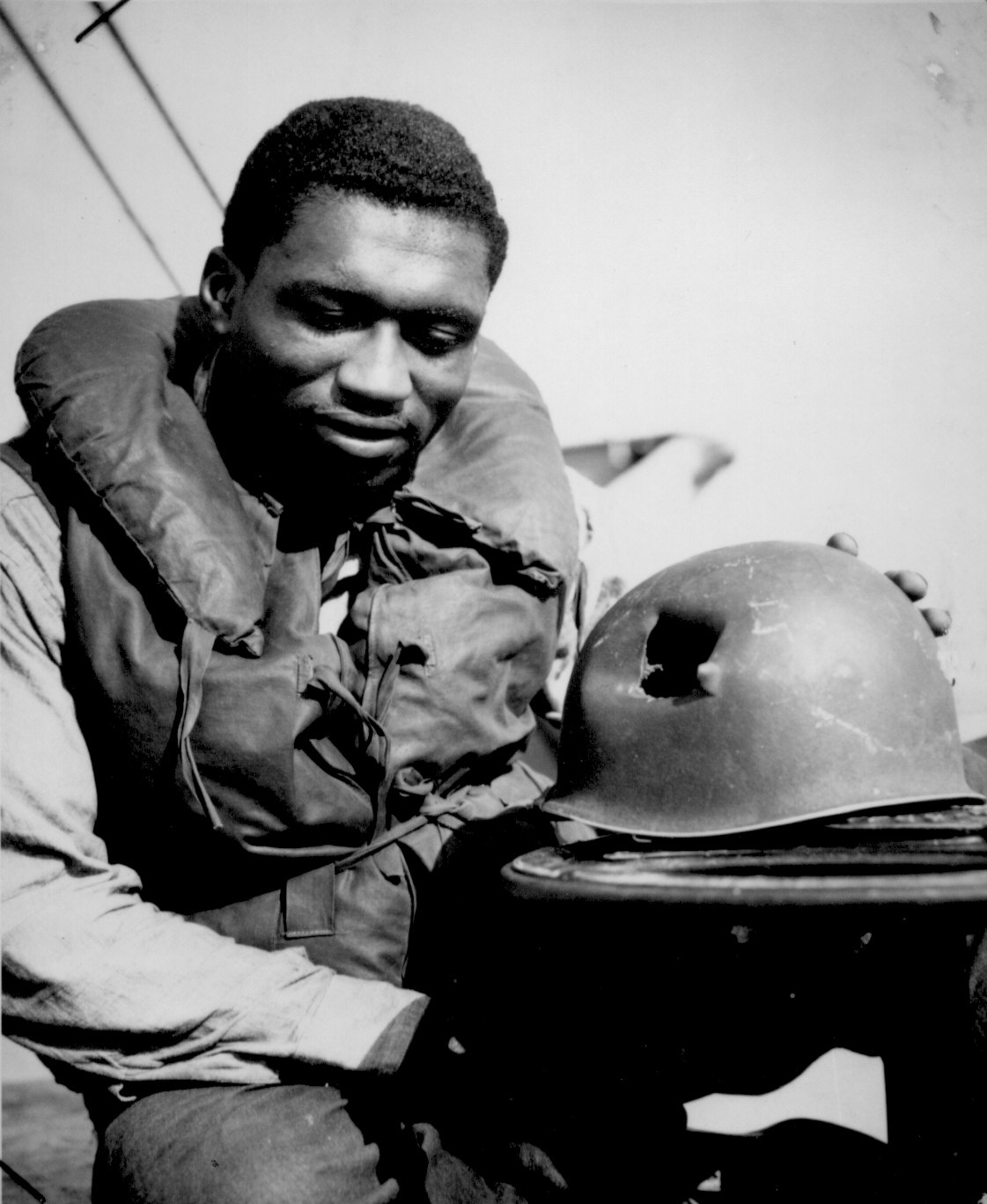 African-American US Coast Guardsman Fireman 1st Class Charles Tyner displaying his helmet, damaged by large shrapnel during the invasion of Southern France, circa late 1944