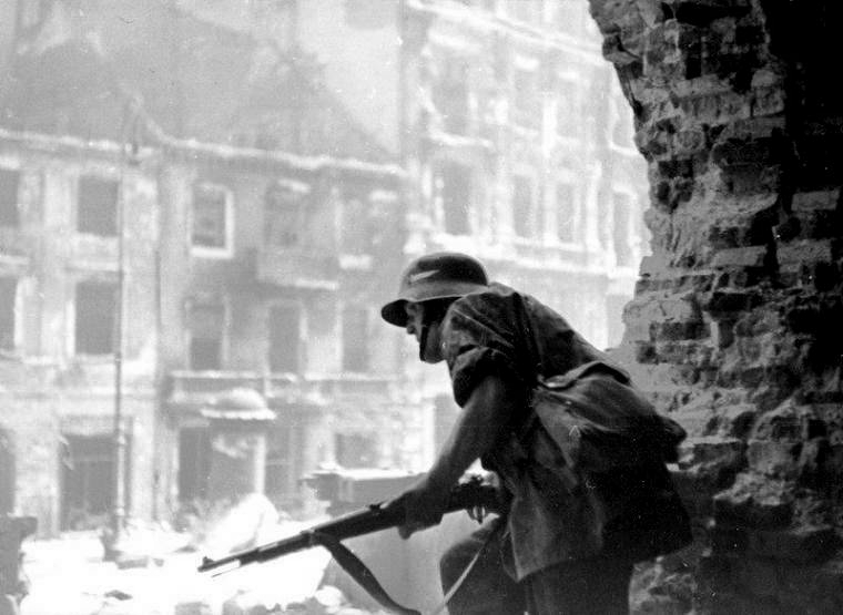 Polish resistance fighter near Krakowskie Przedmiescie Street, Warsaw, Poland, 23 Aug 1944; note captured German K98 rifle and helmet