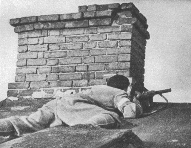 Polish insurgent fighter positioning himself on a roof, Evangelic Cemetery, Warsaw, Poland, 2 Aug 1944