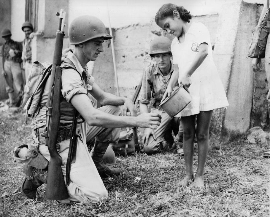US soldier getting water from a girl during a training exercise, Panama Canal Zone, 1942